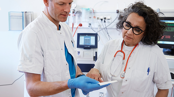 Arts en verpleegkundige controleren resultaten. ABL90 FLEX bloedgasanalyser op de achtergrond
